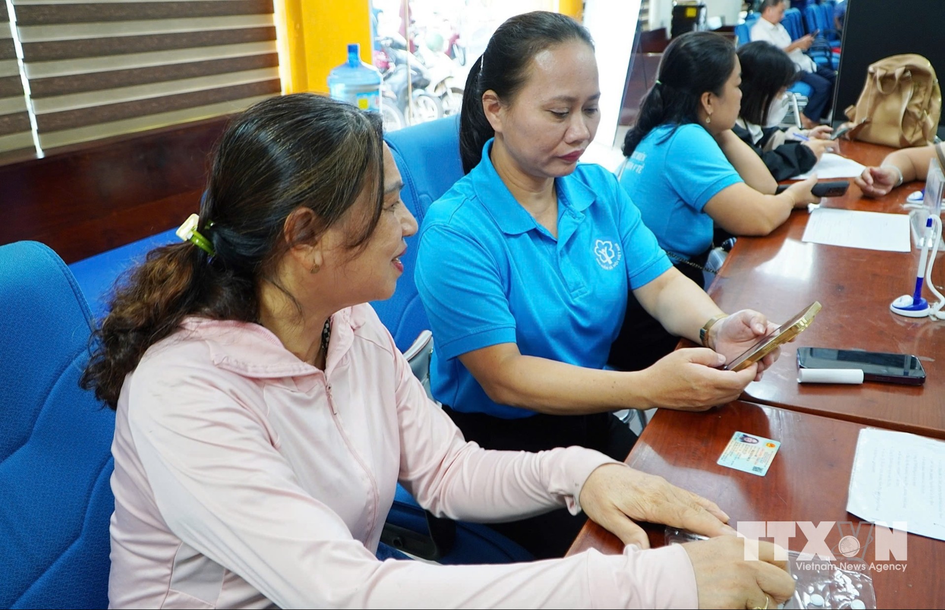 Các cán bộ, nhân viên Bảo hiểm xã hội tỉnh Gia Lai hỗ trợ, hướng dẫn người tham gia bảo hiểm sử dụng ứng dụng VssID. (Ảnh: Quang Thái/TTXVN)